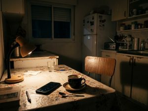 An empty chair at a dimly lit kitchen table, evoking the silence a soldier carries home.